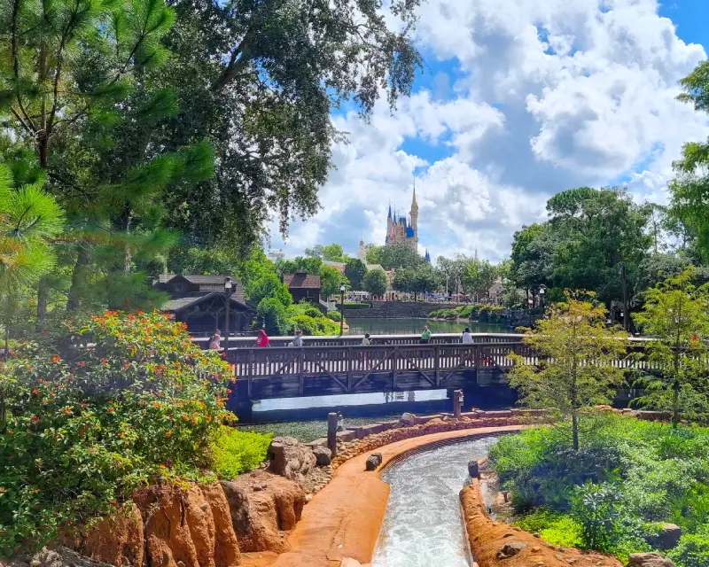 El castillo de la Bella Durmiente en Magic Kingdom rodeado de árboles y un cielo azul