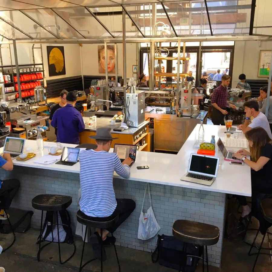 Interior de Intelligentsia Coffee en Venice Beach con personas tomando café y trabajando remoto