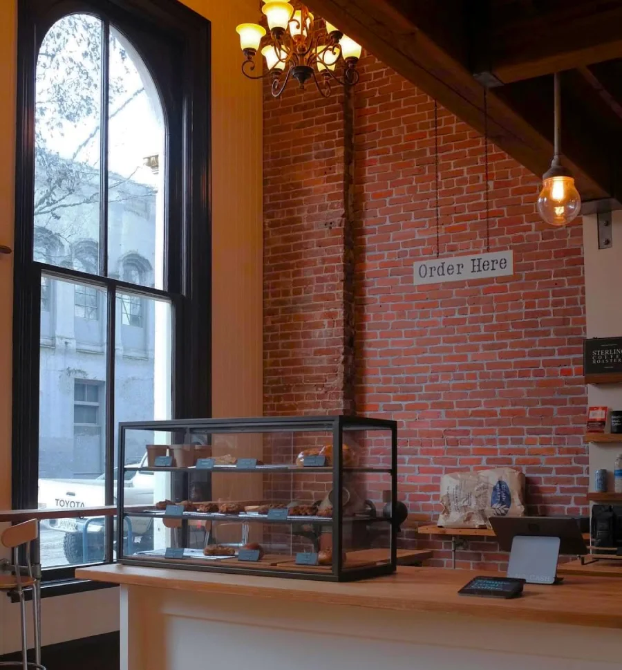 Un rincón acogedor de Simple Local Coffee en Portland Oregón con una gran ventana a un lado y la barra de café al otro