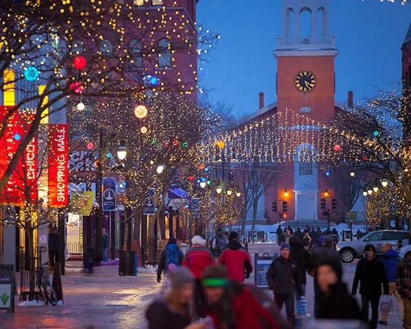 15_lunademiel_burlington Church Street, Burlington, Vermont de noche con guirnaldas de luces iluminando los árboles y personas caminando.