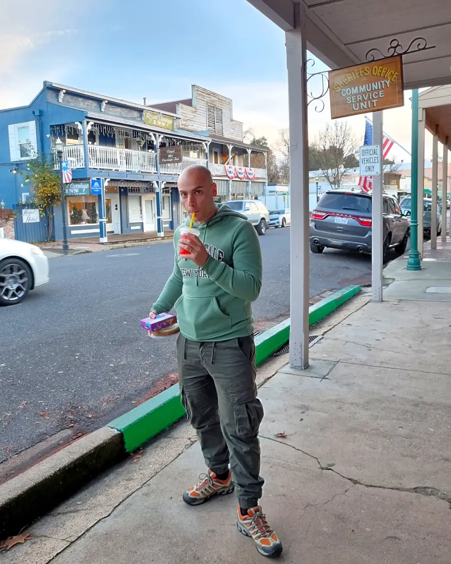Oli bebiendo slurp en Jamestown, California con los edificios históricos detrás