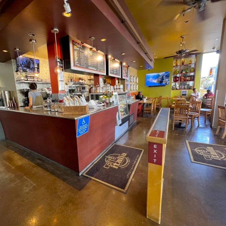 Interior de Caffe Italia en San Diego con algunas mesas vacías al fondo y la barra principal a la izquierda