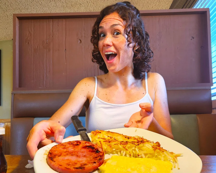 Vico mostrando sonriente su desayuno de jamón, huevos y hashbrowns en un diner de Estados Unidos