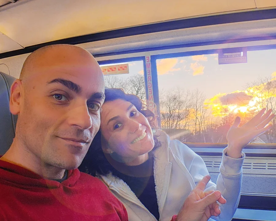 1_de_ny_a_boston_tren Vico y Oli sentados en un vagón viajando en tren de Nueva York a Boston. Por la ventana se ve el atardecer