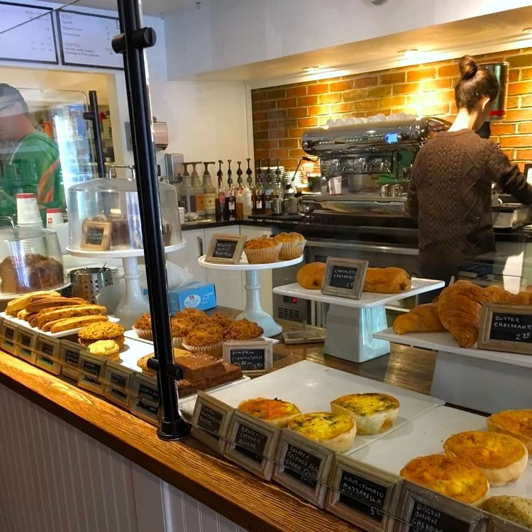 Barra de Three fifty coffee shop en Washington DC con pasteles y quiches salados y un barista preparando café en el fondo