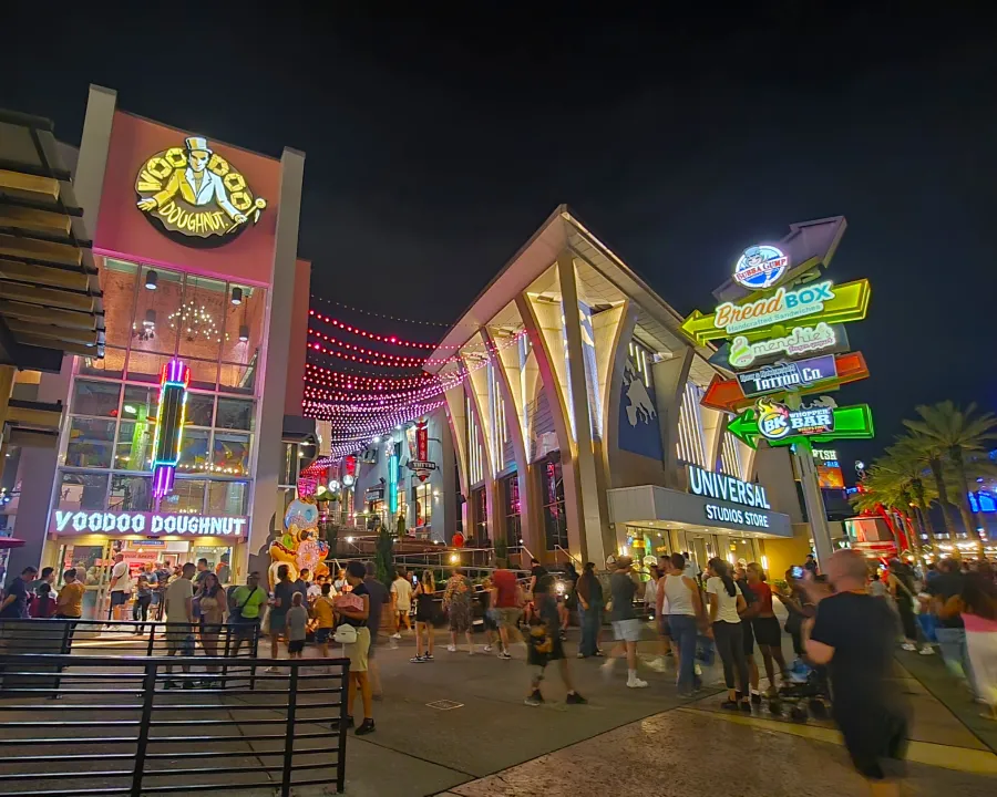 Universal City Walk de noche con las tiendas, restaurantes y carteles iluminados con muchos colores en Universal Orlando