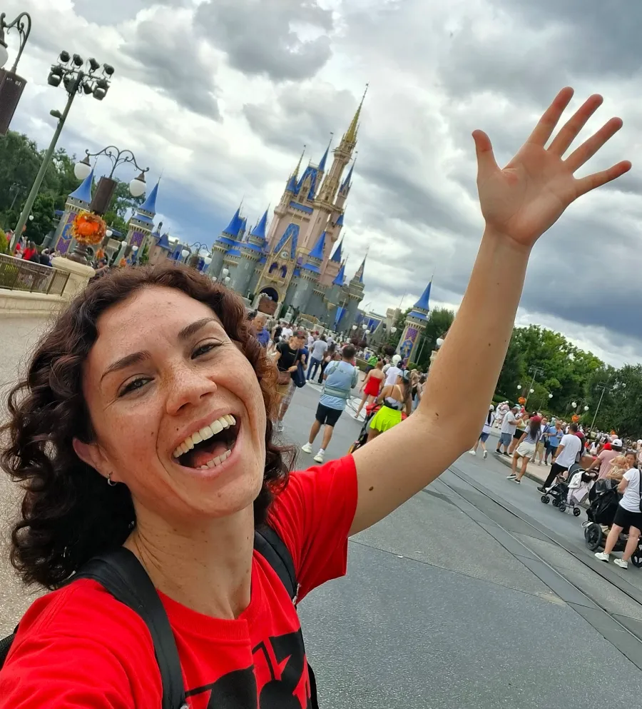Vico sonriendo divertida frente al castillo de la Bella Durmiente en Magic Kingdom de Disney World. Uno de los mejores parques de Orlando para adultos