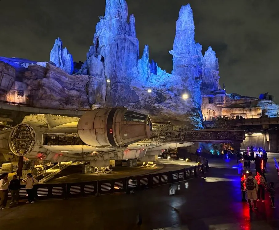 Star Wars Edge en Disney Hollywood Studios de noche con las naves iluminadas y las montañas azules detrás